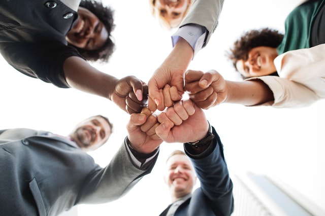 professionals standing outside fist bumping as a group