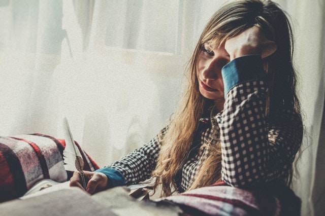 woman indoors upset holding a notebook