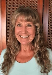 Photo of Angela Gould indoors standing in front of a paneled door wearing a mint green shirt