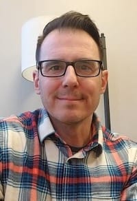 Therapist Michael Gyorffy indoors wearing a plaid button-down shirt