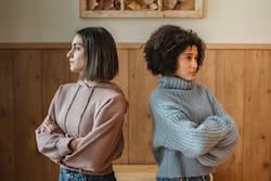 two upset women facing away from each other with their hands crossed