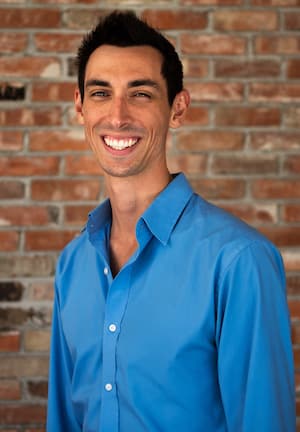 Therapist Desmond Cohen wearing a blue shirt standing by a brick wall