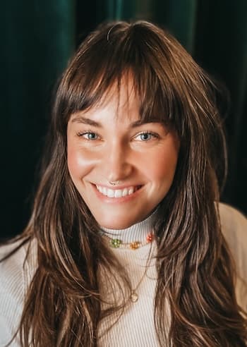 Therapist Hillary Walker smiling in front of dark background and beige top