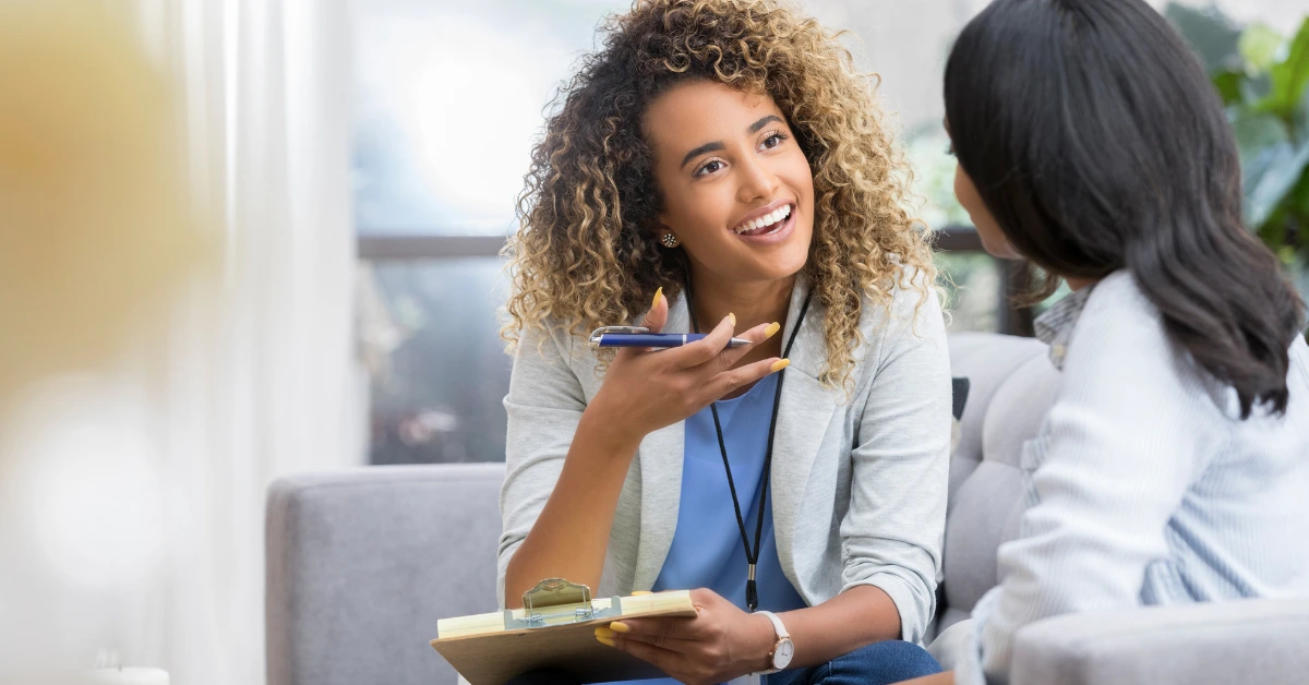 Client speaking with a smiling counselor during a session, illustrating how to find a therapist in Denver.