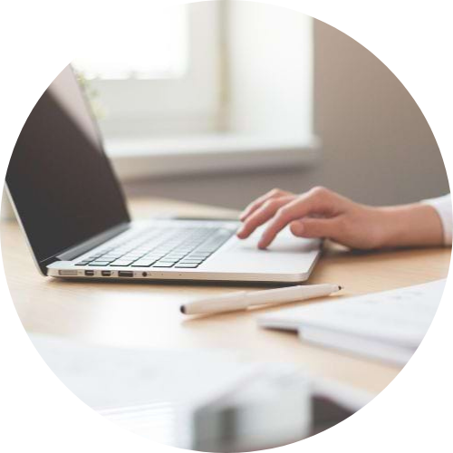 A hand is seen working on a laptop on a desk.