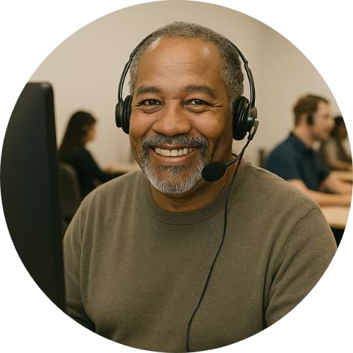 A Black man sitting at a computer with a headset on.