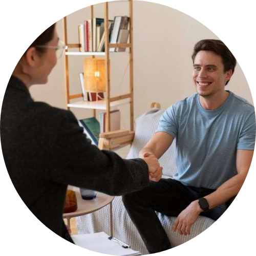 Woman therapist shaking hands with a male patient in a therapy session.